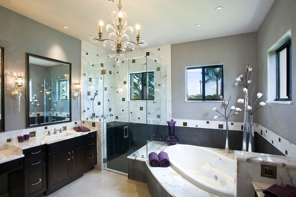 Design ideas for a mid-sized contemporary master bathroom in Miami with shaker cabinets, brown cabinets, a drop-in tub, a corner shower, white tile, marble, grey walls, travertine floors, an undermount sink, marble benchtops, beige floor and a hinged shower door.
