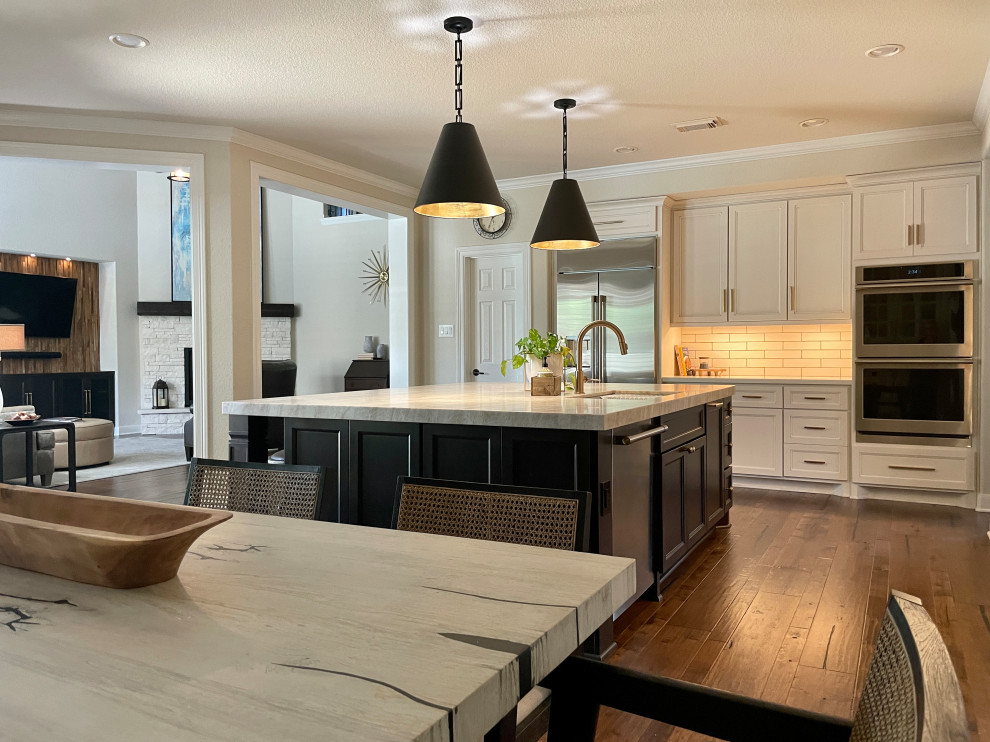 Inspiration for a large l-shaped kitchen/diner in Houston with a submerged sink, flat-panel cabinets, distressed cabinets, quartz worktops, white splashback, ceramic splashback, stainless steel appliances, medium hardwood flooring, an island, brown floors and beige worktops.