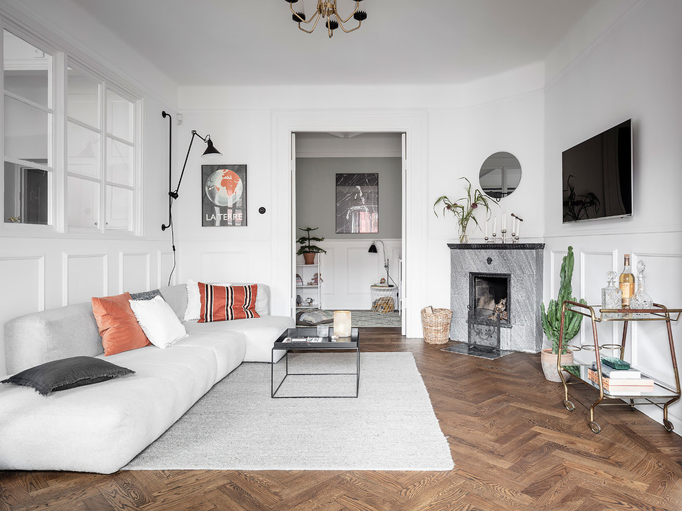 This is an example of a mid-sized scandinavian enclosed living room in Gothenburg with white walls, medium hardwood floors, brown floor, a corner fireplace and a wall-mounted tv.