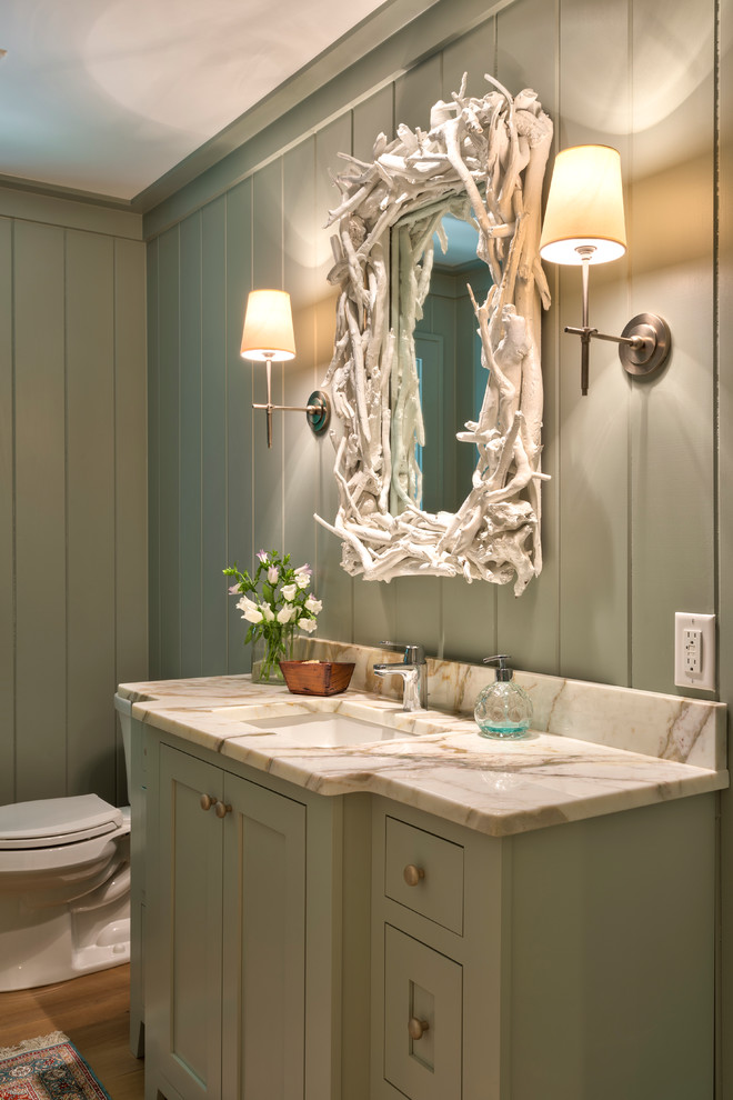Photo of a mid-sized beach style 3/4 bathroom in Miami with shaker cabinets, green cabinets, a two-piece toilet, beige tile, green walls, an undermount sink, solid surface benchtops, medium hardwood floors and brown floor.