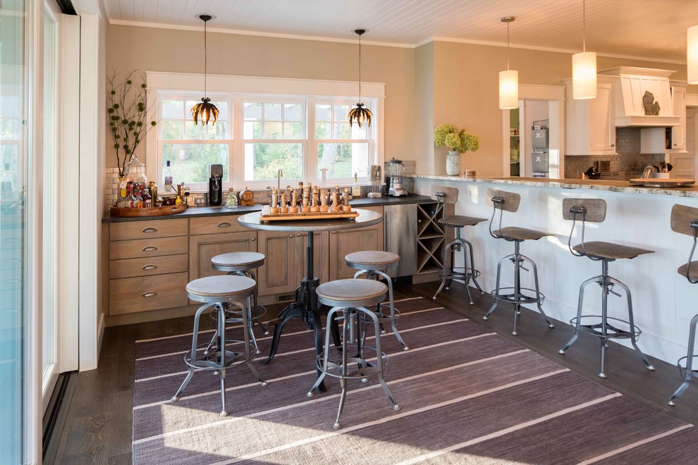 Mid-sized transitional single-wall dark wood floor and brown floor wet bar photo with recessed-panel cabinets, distressed cabinets, gray backsplash, metal backsplash, black countertops, an undermount sink and soapstone countertops
