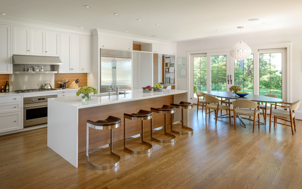 This is an example of a large transitional l-shaped eat-in kitchen in Seattle with flat-panel cabinets, medium wood cabinets, quartz benchtops, with island, brown splashback, medium hardwood floors, an undermount sink, timber splashback, stainless steel appliances and brown floor.