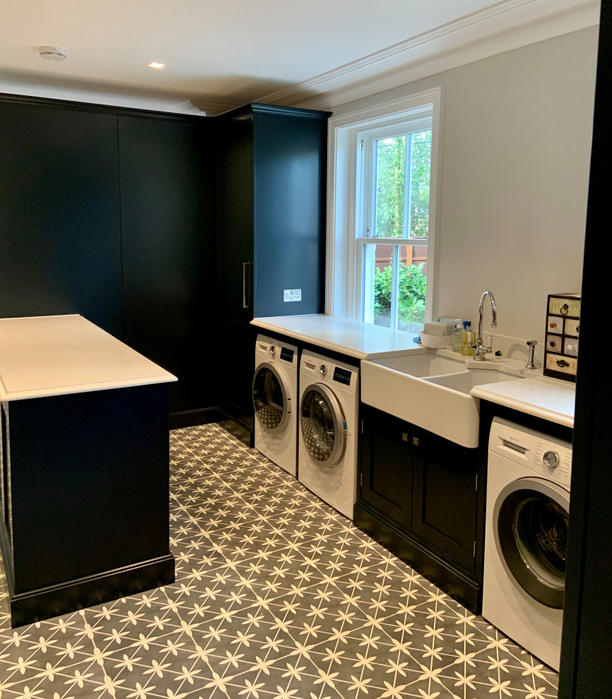 Inspiration for an expansive traditional galley laundry room in Hampshire with an undermount sink, shaker cabinets, black cabinets, quartzite benchtops, white splashback, stone slab splashback, medium hardwood floors, brown floor and white benchtop.