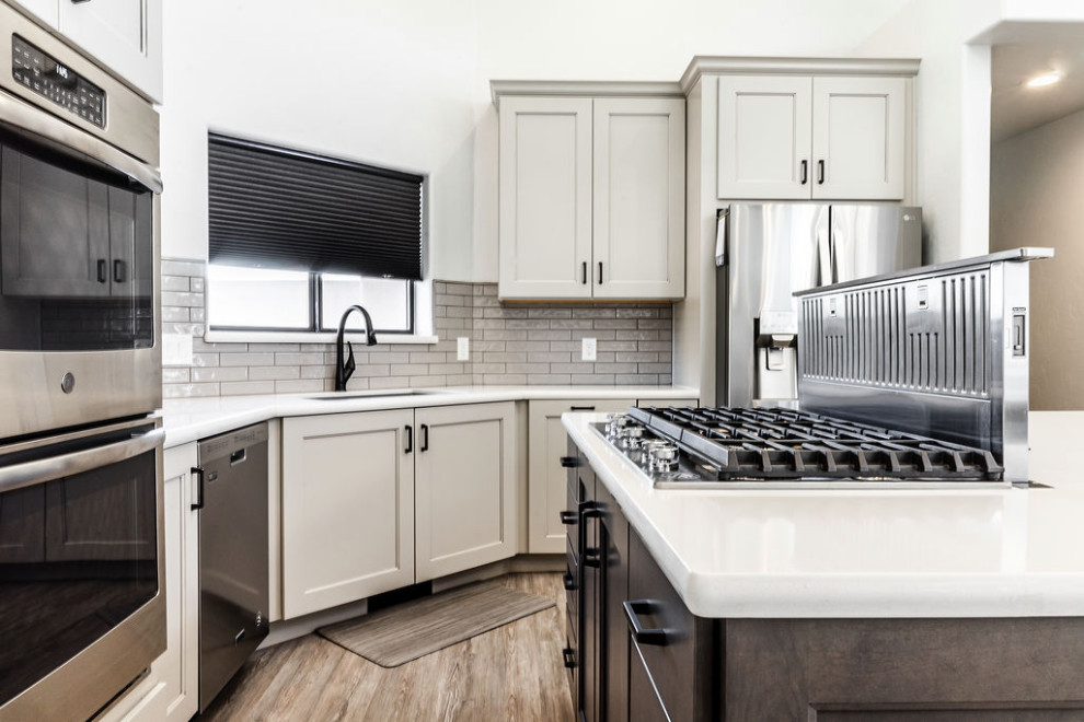 Large transitional u-shaped vinyl floor and gray floor eat-in kitchen photo with an undermount sink, shaker cabinets, gray cabinets, quartzite countertops, green backsplash, subway tile backsplash, stainless steel appliances, an island and white countertops