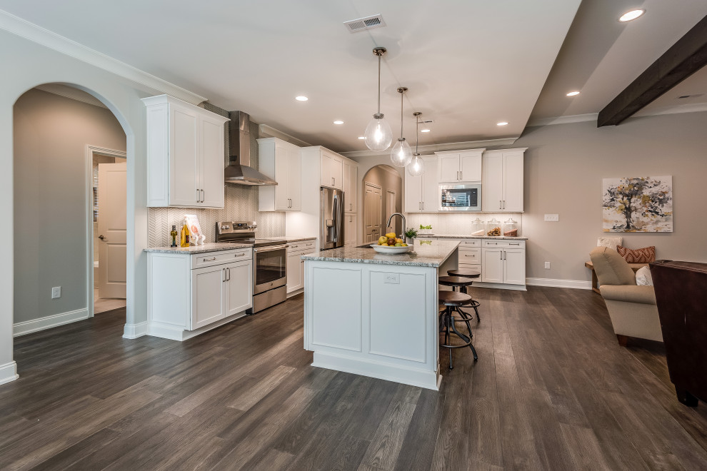 Example of a mid-sized transitional l-shaped open concept kitchen design with an undermount sink, flat-panel cabinets, white cabinets, quartz countertops, white backsplash, glass tile backsplash, stainless steel appliances, an island and white countertops