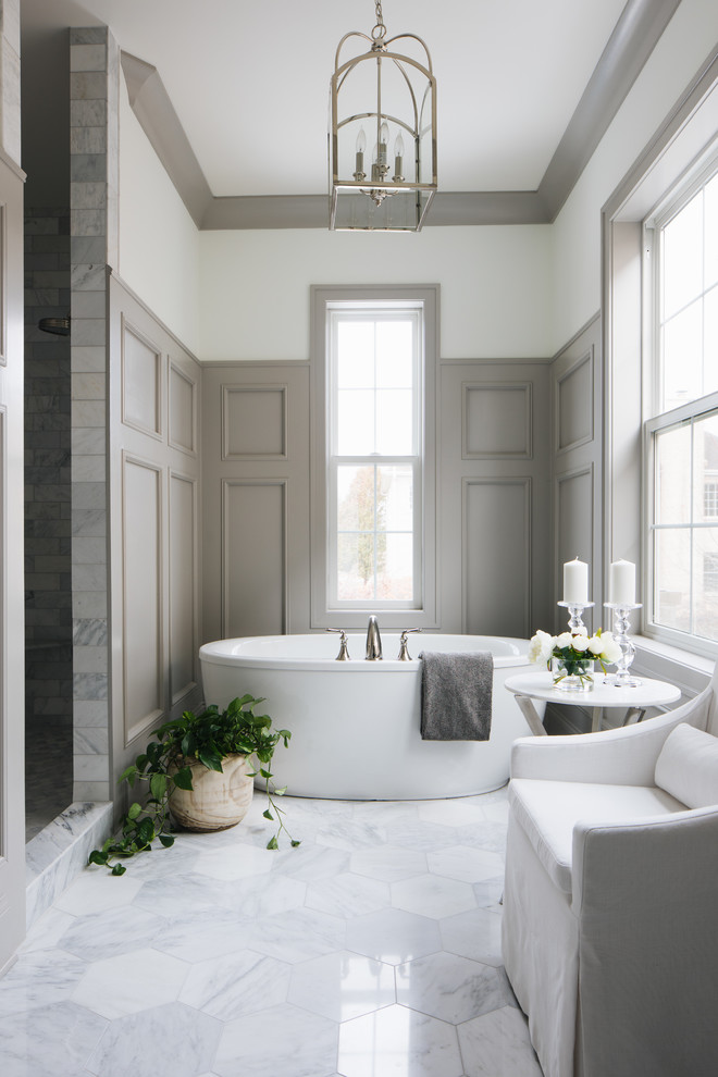 Transitional bathroom in Chicago with a freestanding tub, an alcove shower, gray tile, beige walls and white floor.