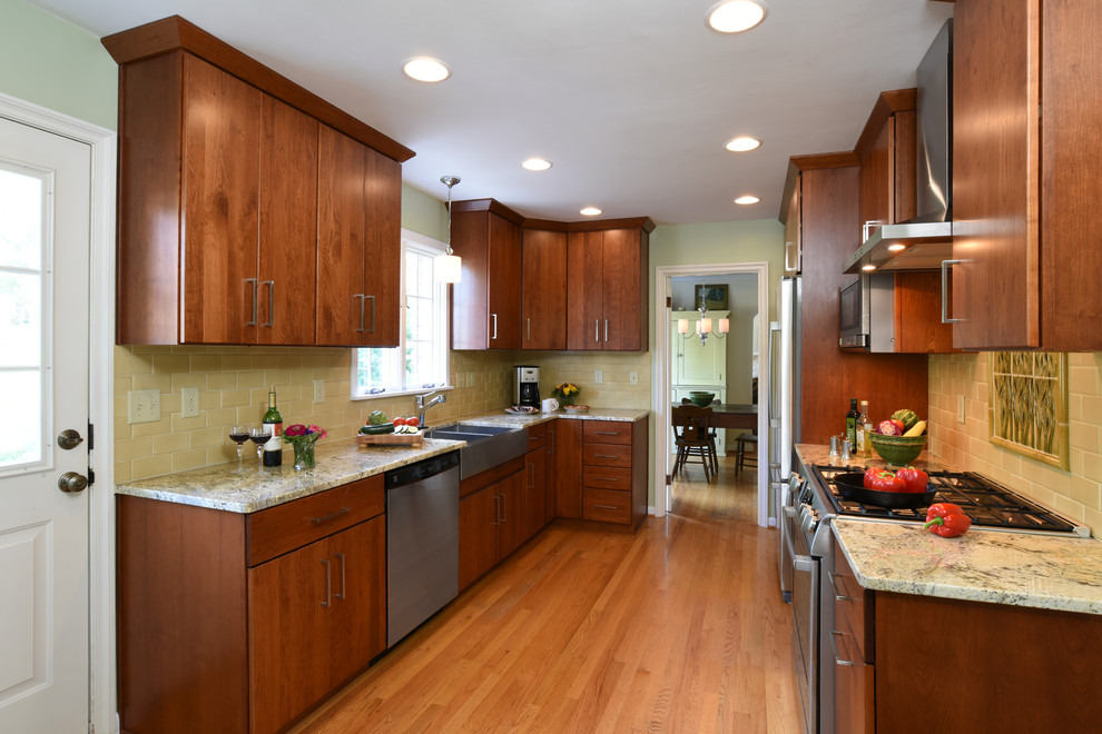 Enclosed kitchen - mid-sized transitional galley light wood floor enclosed kitchen idea with a farmhouse sink, flat-panel cabinets, medium tone wood cabinets, granite countertops, yellow backsplash, ceramic backsplash, stainless steel appliances and no island