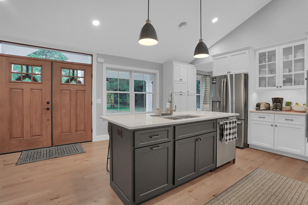 Example of a mid-sized transitional l-shaped open concept kitchen design with flat-panel cabinets, white cabinets, quartz countertops, gray backsplash, an island and white countertops