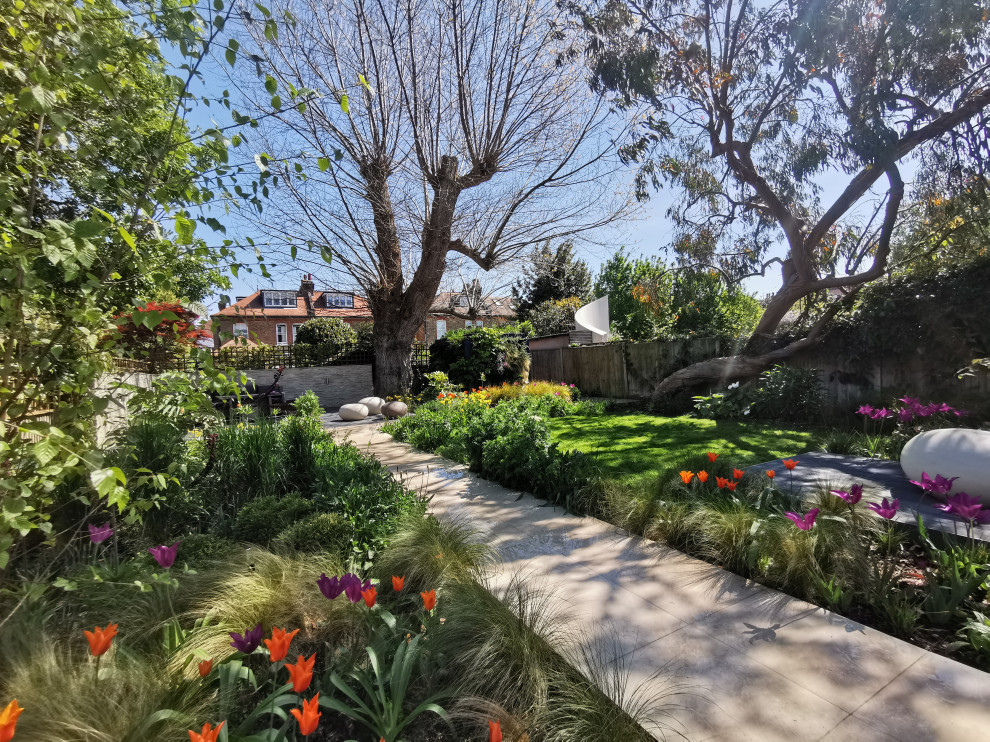 Esempio di un giardino xeriscape contemporaneo esposto a mezz'ombra di medie dimensioni e dietro casa in primavera con un ingresso o sentiero, pavimentazioni in pietra naturale e recinzione in legno