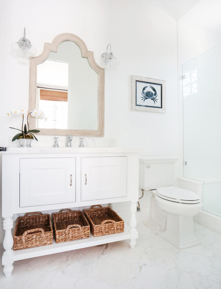 This is an example of a beach style bathroom in Orange County with an alcove shower, a one-piece toilet and marble floors.