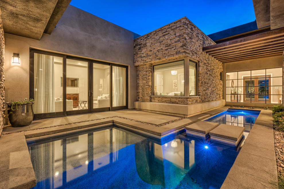 Inspiration for a large modern backyard custom-shaped lap pool in Las Vegas with a hot tub and concrete pavers.