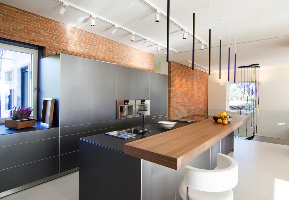 Example of a mid-sized trendy single-wall open concept kitchen design in Barcelona with flat-panel cabinets, gray cabinets, stainless steel appliances and an island