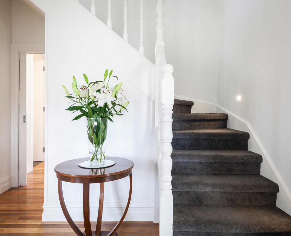 This is an example of a mid-sized contemporary carpeted l-shaped staircase in Melbourne with carpet risers.