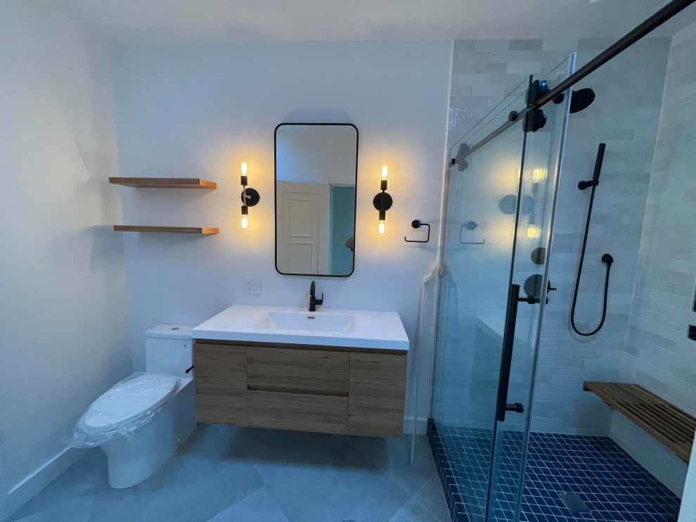 Idéer för ett mellanstort nordiskt vit badrum med dusch, med släta luckor, bruna skåp, en toalettstol med hel cisternkåpa, vit kakel, porslinskakel, grå väggar, klinkergolv i porslin, ett integrerad handfat, bänkskiva i akrylsten, grått golv och dusch med skjutdörr