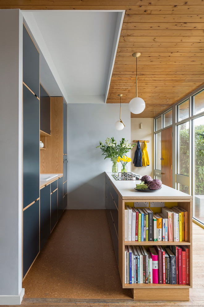 Inspiration for a contemporary galley kitchen in London with a drop-in sink, flat-panel cabinets, blue cabinets, light hardwood floors and a peninsula.