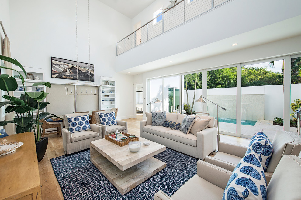 Inspiration for a beach style open concept living room in Miami with white walls and light hardwood floors.