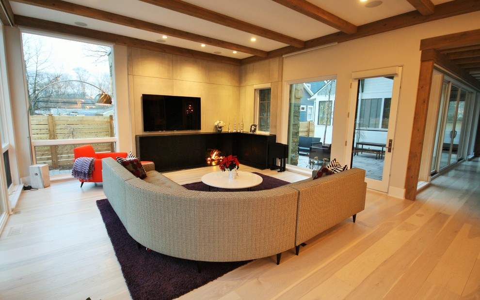 Large contemporary enclosed family room in Chicago with brown walls, light hardwood floors, a standard fireplace, a wall-mounted tv and brown floor.