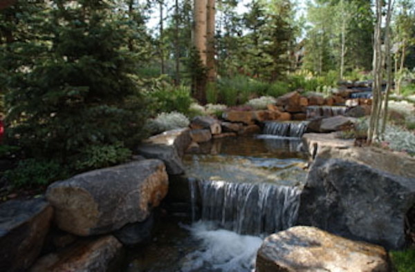 This is an example of a huge rustic full sun backyard stone water fountain landscape in Denver.