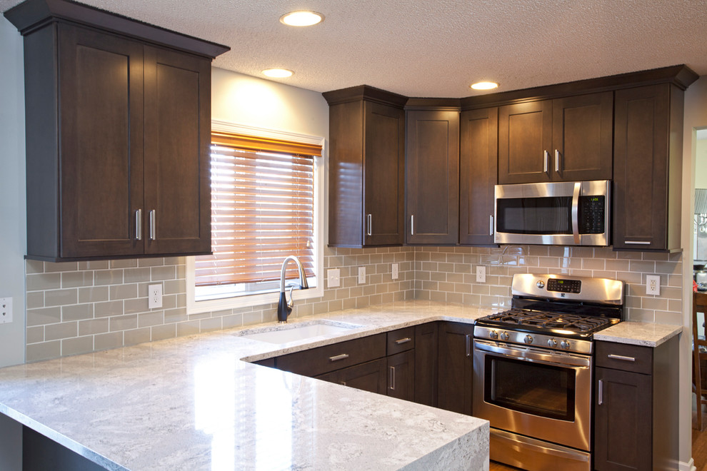 Example of a mid-sized transitional u-shaped medium tone wood floor eat-in kitchen design in Minneapolis with an undermount sink, flat-panel cabinets, dark wood cabinets, gray backsplash, glass tile backsplash, stainless steel appliances and a peninsula