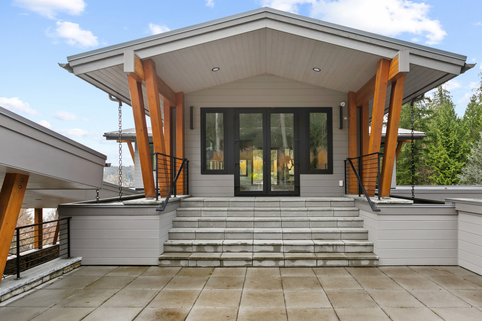Diseño de fachada de casa gris y gris extra grande de tres plantas con revestimiento de hormigón y tejado de metal