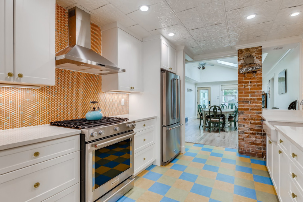 Small galley enclosed kitchen in Denver with a belfast sink, shaker cabinets, white cabinets, engineered stone countertops, orange splashback, mosaic tiled splashback, stainless steel appliances, lino flooring, no island, blue floors, white worktops and a drop ceiling.