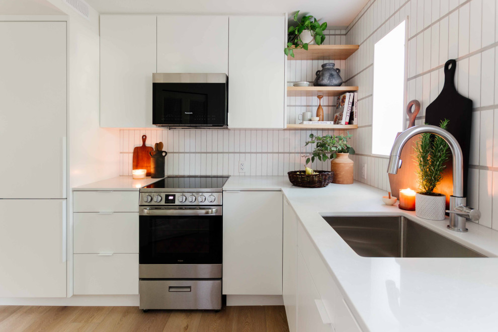 Design ideas for a small contemporary l-shaped separate kitchen in Vancouver with an undermount sink, flat-panel cabinets, white cabinets, quartz benchtops, white splashback, ceramic splashback, panelled appliances, vinyl floors, no island, brown floor and grey benchtop.