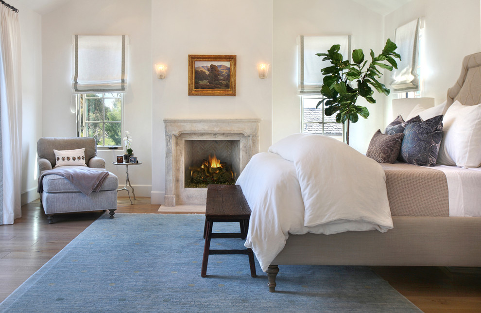 Mediterranean master bedroom in Orange County with white walls and a standard fireplace.