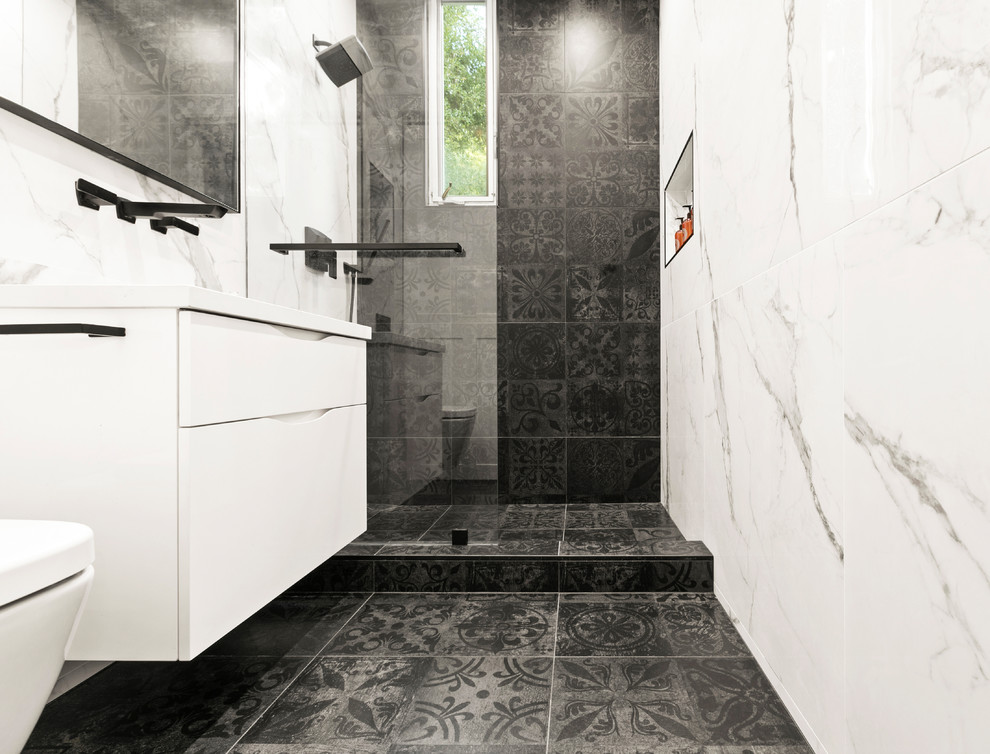 Inspiration for a mid-sized transitional bathroom in Los Angeles with flat-panel cabinets, white cabinets, a wall-mount toilet, black and white tile, porcelain tile, white walls, porcelain floors, black floor and white benchtops.