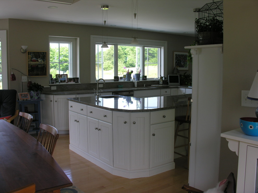 Large traditional l-shaped eat-in kitchen in Portland Maine with an undermount sink, louvered cabinets, white cabinets, granite benchtops, grey splashback, stone slab splashback, white appliances, light hardwood floors and with island.