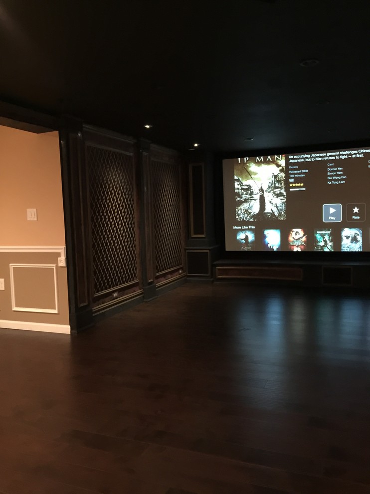 This is an example of a mid-sized mediterranean open concept home theatre in New York with dark hardwood floors, a projector screen and red walls.