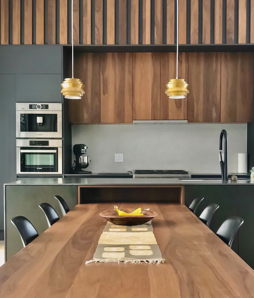 Cette image montre une cuisine américaine minimaliste en bois foncé de taille moyenne avec un placard à porte plane, plan de travail carrelé, une crédence beige, parquet clair, îlot et plan de travail noir.