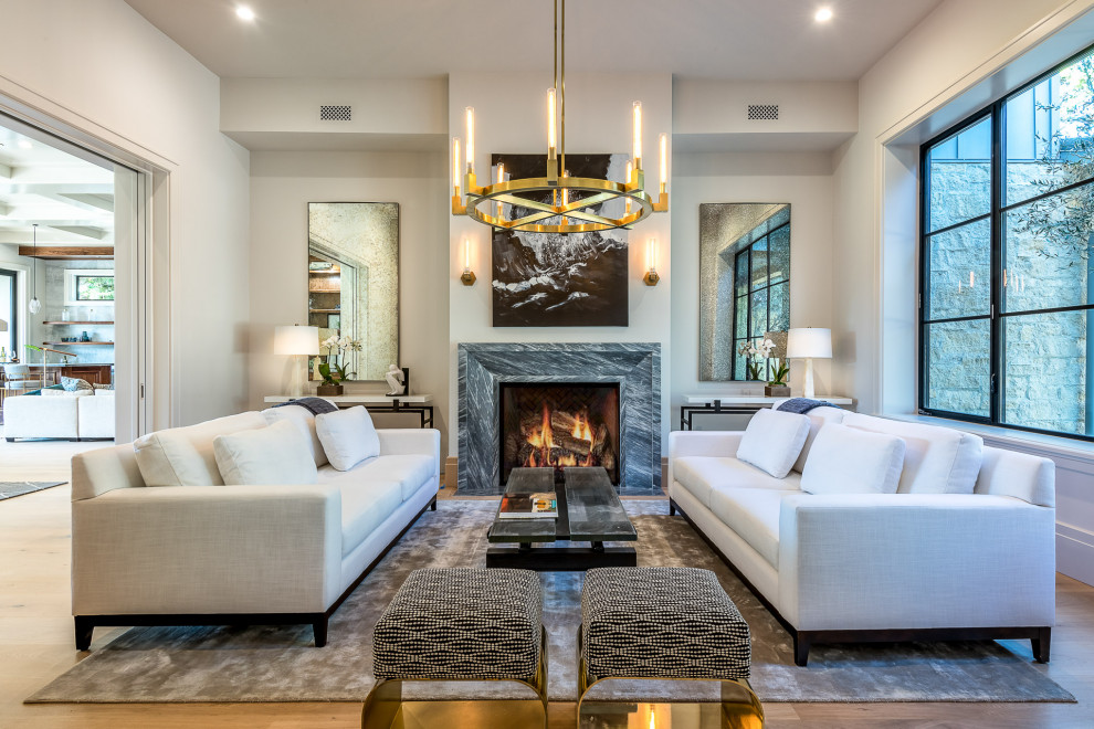 Photo of an expansive transitional living room in Los Angeles with white walls, light hardwood floors, a standard fireplace, a stone fireplace surround, beige floor and coffered.
