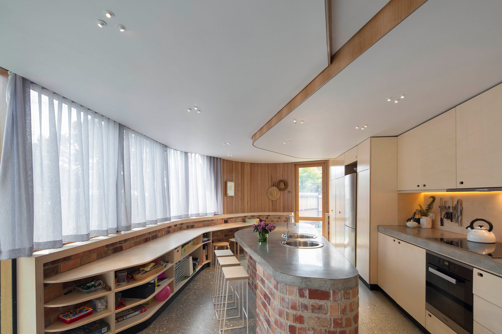 Mid-sized contemporary galley separate kitchen in Melbourne with flat-panel cabinets, light wood cabinets, concrete benchtops, beige splashback, stainless steel appliances, with island, grey floor and timber splashback.