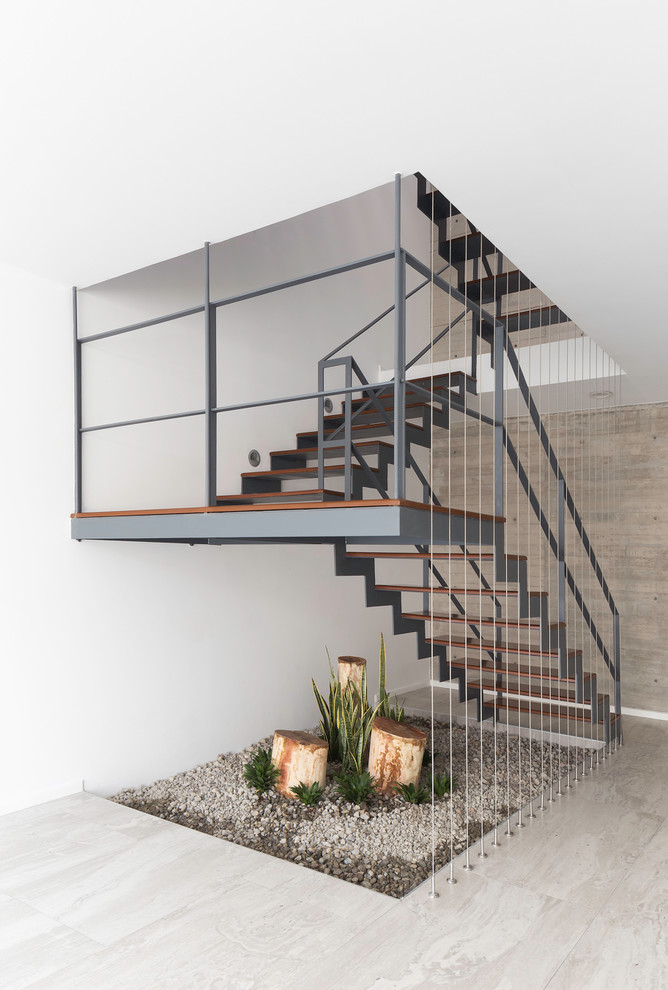Contemporary wood u-shaped staircase with open risers and metal railing.