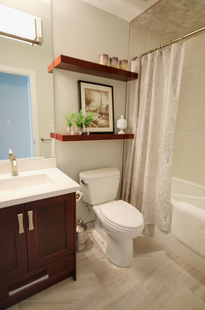 Inspiration for a small traditional master bathroom in Calgary with an undermount sink, recessed-panel cabinets, dark wood cabinets, solid surface benchtops, an alcove tub, an alcove shower, a two-piece toilet, gray tile, porcelain tile, white walls and porcelain floors.