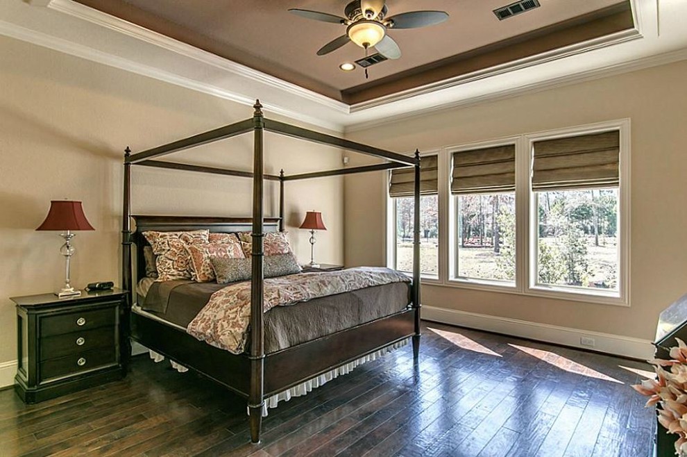 Photo of a mid-sized mediterranean master bedroom in Houston with beige walls and dark hardwood floors.