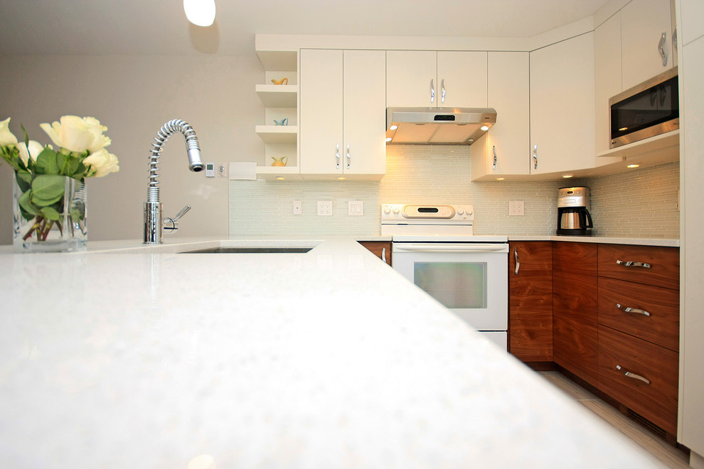 Mid-sized contemporary u-shaped kitchen in Vancouver with flat-panel cabinets, medium wood cabinets, quartz benchtops, beige splashback, glass tile splashback, stainless steel appliances and porcelain floors.