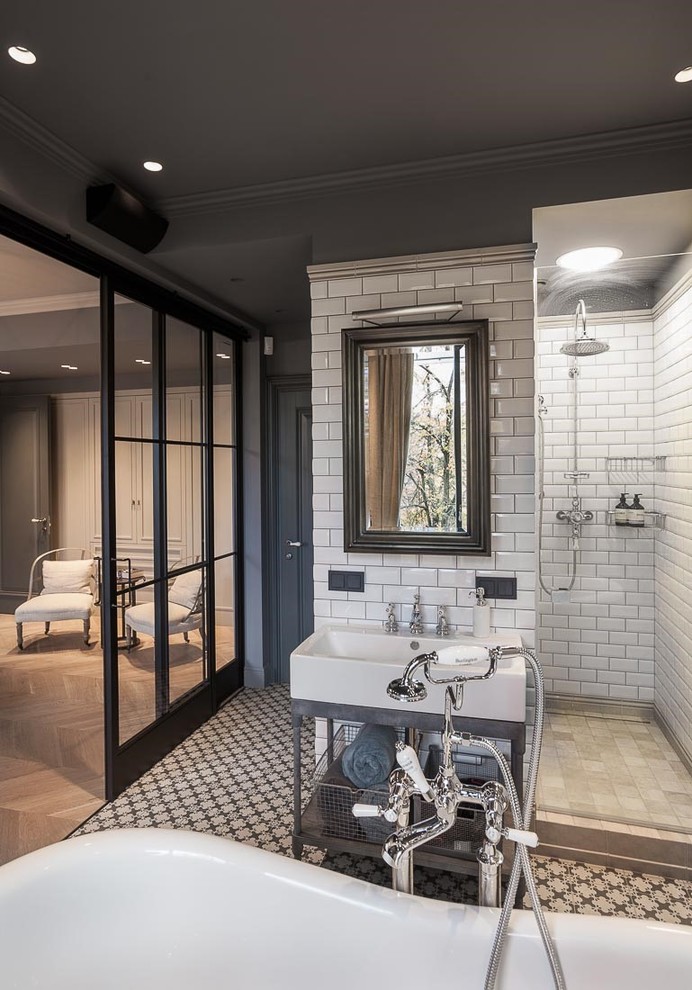 Mid-sized industrial master bathroom in London with shaker cabinets, grey cabinets, a freestanding tub, an open shower, gray tile, subway tile, grey walls, porcelain floors and a wall-mount sink.
