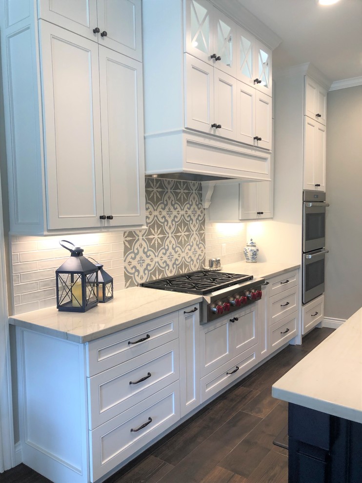 Transitional kitchen in Houston with a drop-in sink, shaker cabinets, white cabinets, quartzite benchtops, white splashback, stainless steel appliances, porcelain floors, multiple islands, brown floor and white benchtop.