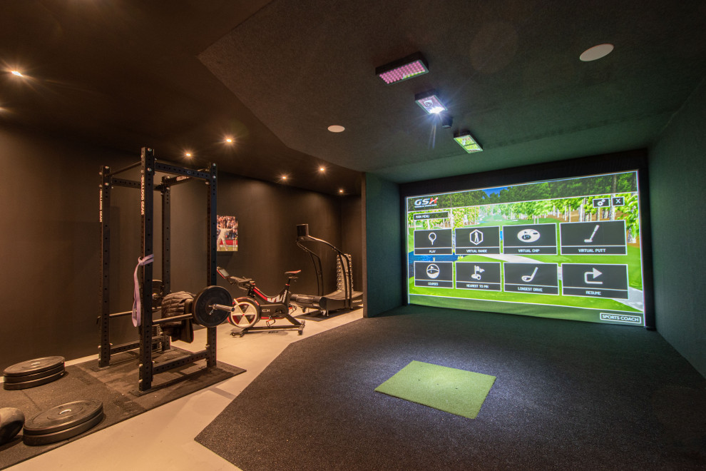 This is an example of a large modern enclosed games room with a game room, black walls, carpet, a wall mounted tv and grey floors.
