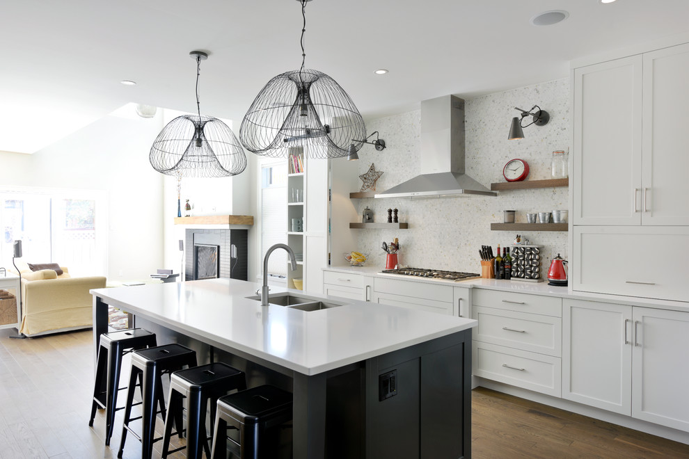 This is an example of a transitional galley kitchen in Toronto with an undermount sink, shaker cabinets, white cabinets, white splashback, mosaic tile splashback, dark hardwood floors, with island and brown floor.