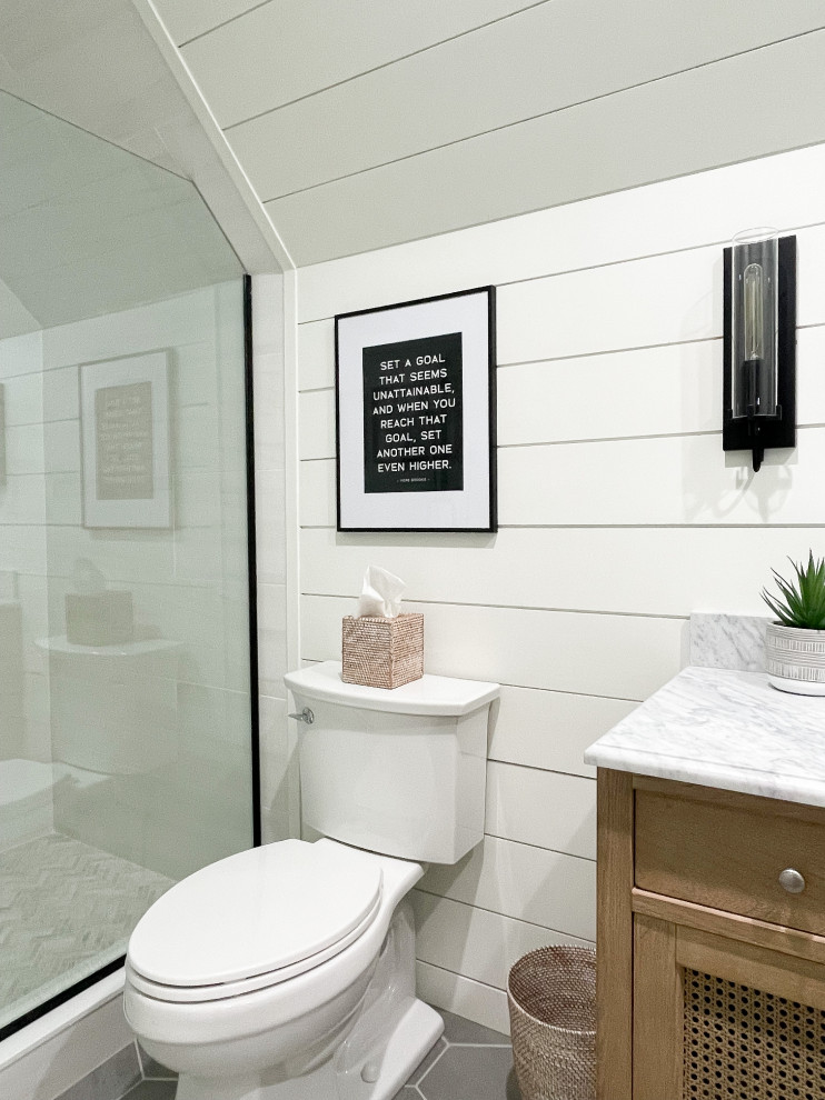 Bild på ett mellanstort lantligt grå grått badrum för barn, med luckor med infälld panel, skåp i mellenmörkt trä, en dusch i en alkov, en toalettstol med separat cisternkåpa, vit kakel, porslinskakel, vita väggar, klinkergolv i porslin, ett undermonterad handfat, marmorbänkskiva, grått golv och dusch med gångjärnsdörr