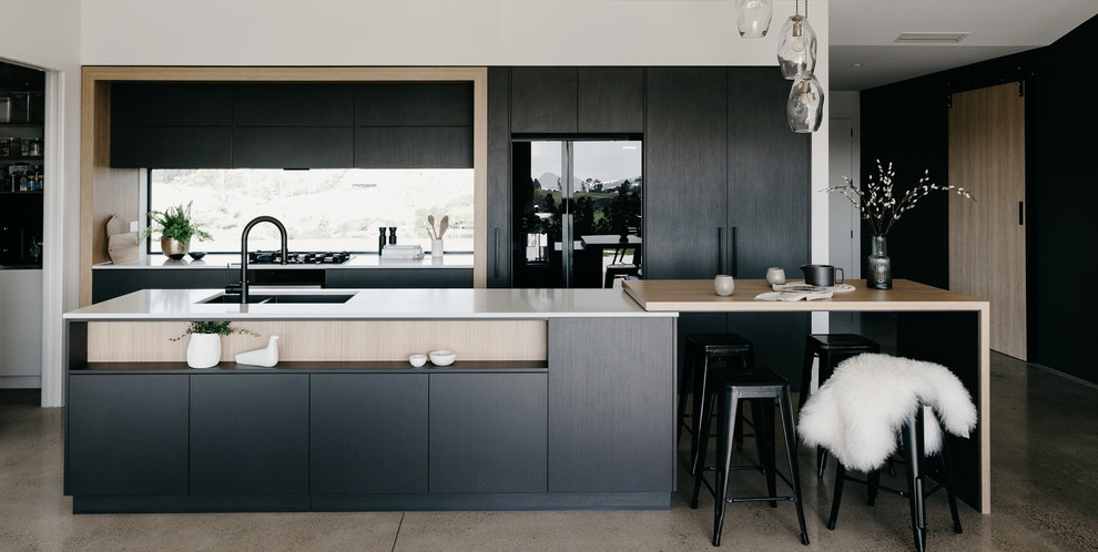 Photo of a large contemporary galley eat-in kitchen in Other with an undermount sink, flat-panel cabinets, grey cabinets, quartz benchtops, white splashback, window splashback, black appliances, concrete floors, with island, grey floor and white benchtop.
