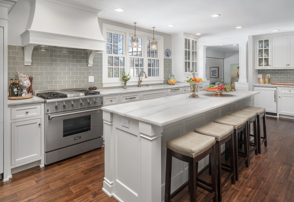 Transitional kitchen in Minneapolis with an undermount sink, shaker cabinets, white cabinets, grey splashback, stainless steel appliances, dark hardwood floors, with island and white benchtop.