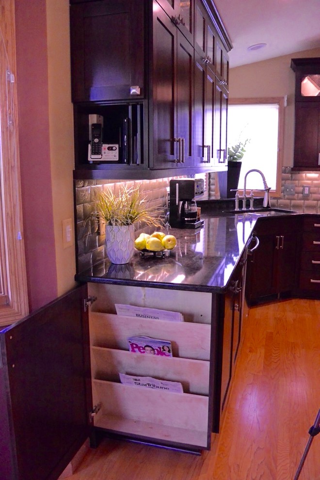 Modern inredning av ett kök, med en undermonterad diskho, skåp i shakerstil, skåp i mörkt trä, bänkskiva i kvarts, stänkskydd med metallisk yta, stänkskydd i glaskakel, rostfria vitvaror, mellanmörkt trägolv och en köksö