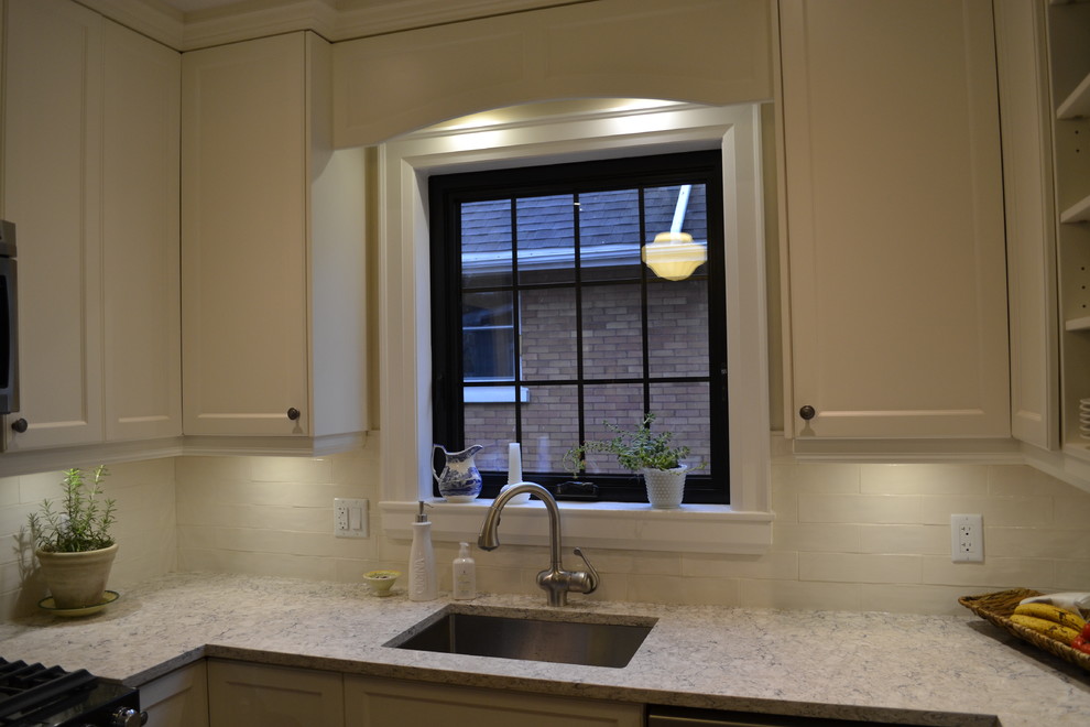 Inspiration for a small transitional galley medium tone wood floor enclosed kitchen remodel in Toronto with an undermount sink, recessed-panel cabinets, white cabinets, white backsplash, porcelain backsplash, stainless steel appliances, no island and quartz countertops