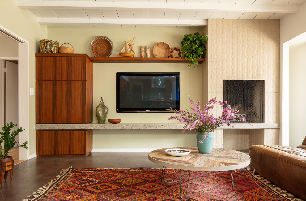 Photo of a large midcentury formal open concept living room in Los Angeles with green walls, concrete floors, a standard fireplace, a tile fireplace surround, a wall-mounted tv, grey floor and exposed beam.