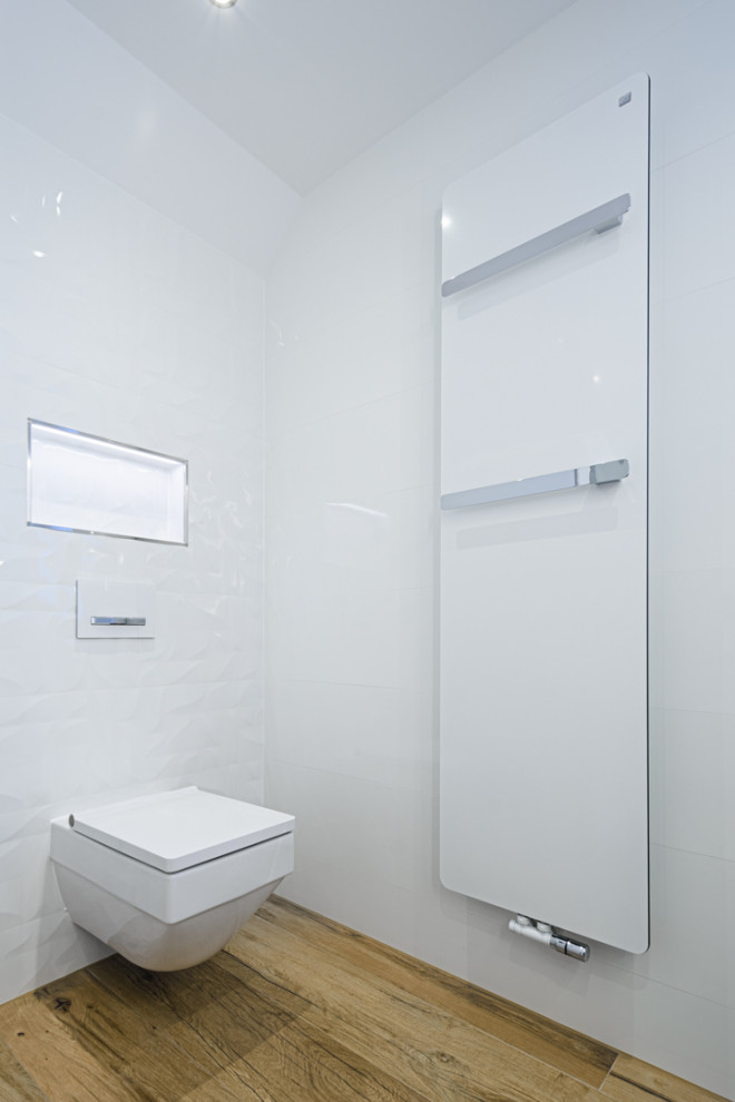 Modelo de cuarto de baño contemporáneo con puertas de armario de madera en tonos medios, combinación de ducha y bañera, sanitario de dos piezas, baldosas y/o azulejos blancos, paredes blancas, imitación a madera, suelo marrón y ducha con puerta corredera