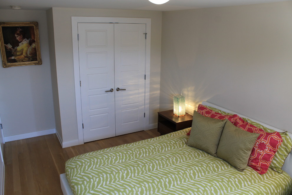 This is an example of a mid-sized beach style guest bedroom in New York with beige walls and medium hardwood floors.