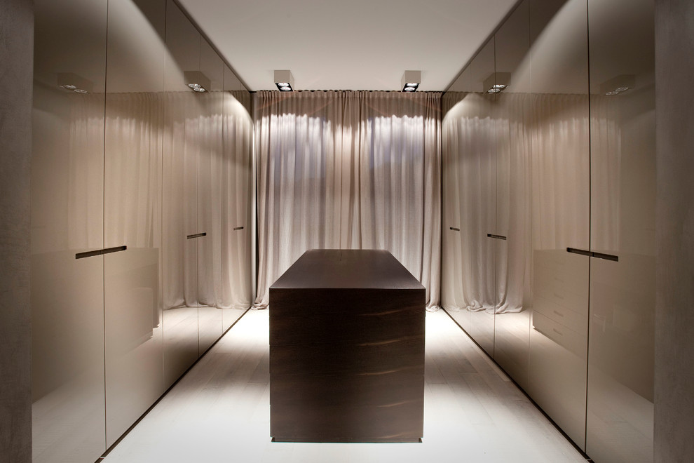 This is an example of an expansive contemporary gender-neutral dressing room in Milan with flat-panel cabinets, brown cabinets and light hardwood floors.
